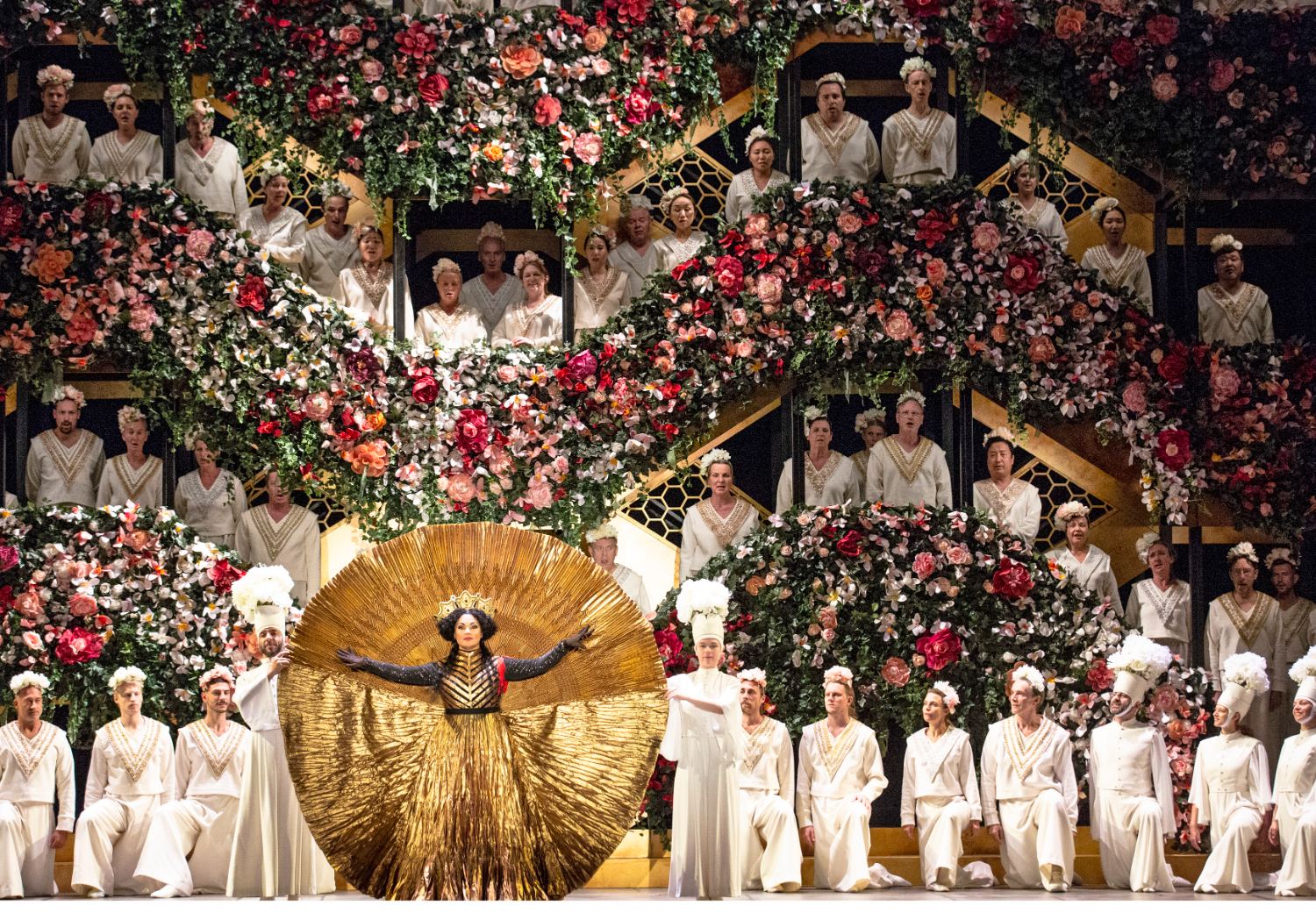 Anna Netrebko als Abigaille im goldenen Fächerkostüm vor der Blumenkulisse